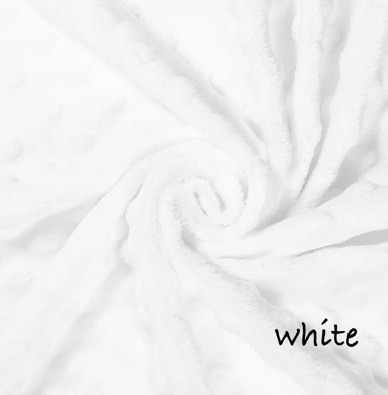 May include: A close-up shot of a soft, white blanket with a swirling pattern. The blanket has a plush texture and is made of a fluffy material. The word "white" is written in a black, cursive font in the bottom right corner.