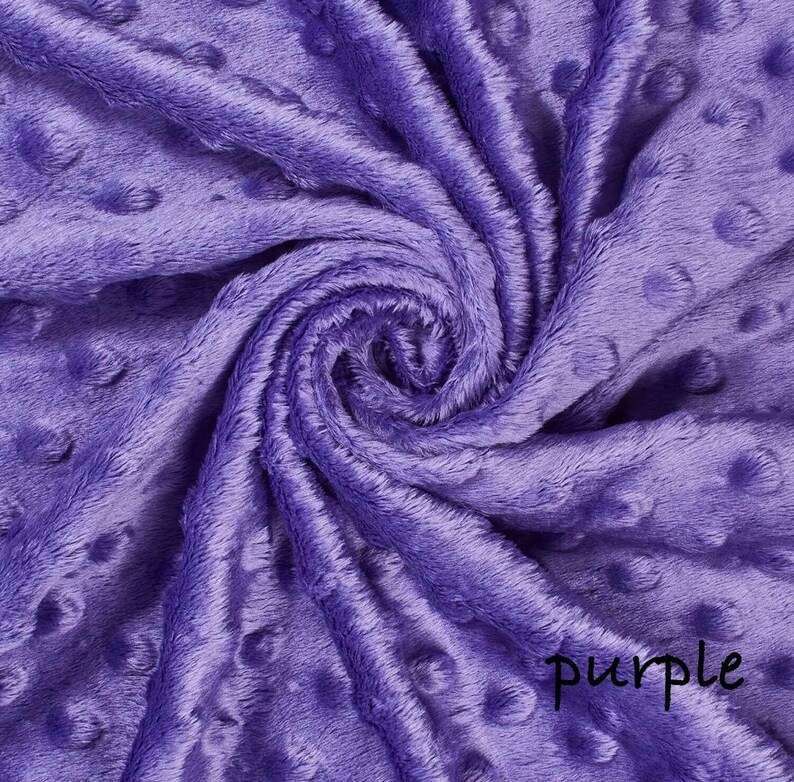 May include: A close-up of a soft, textured fabric in a vibrant purple hue. The fabric has a plush, velvety appearance with a pattern of raised, circular dots. The word "purple" is written in a cursive script on the fabric.