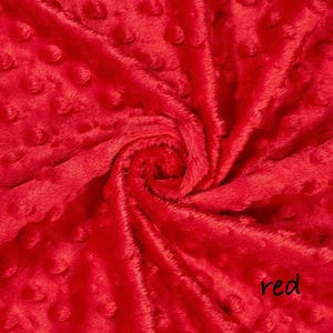 May include: Close-up of a vibrant red fabric with a textured, dotted pattern. The plush material is gathered and swirled, creating a dynamic display of light and shadow. The word "red" is written in a cursive font in the bottom right corner.