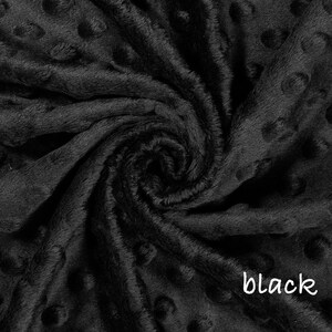 May include: Close-up of a black, textured fabric with a soft, plush appearance. The fabric has a dimpled pattern and is tightly swirled, creating a sense of depth and texture. The word "black" is written in white script in the lower right corner.