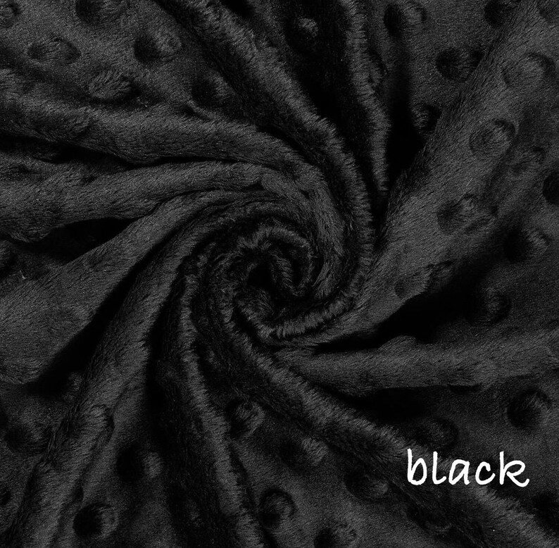 May include: Close-up of a black, textured fabric with a soft, plush appearance. The fabric has a dimpled pattern and is tightly swirled, creating a sense of depth and texture. The word "black" is written in white script in the lower right corner.