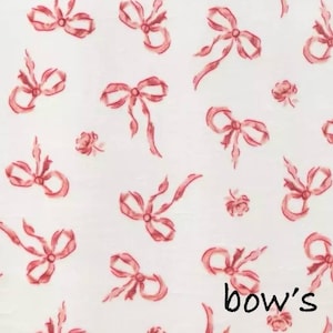 May include: White fabric with a repeating pattern of watercolor-style red bows and small roses. The word "bow's" is written in black script at the bottom right corner of the image. The bows vary in size and style.