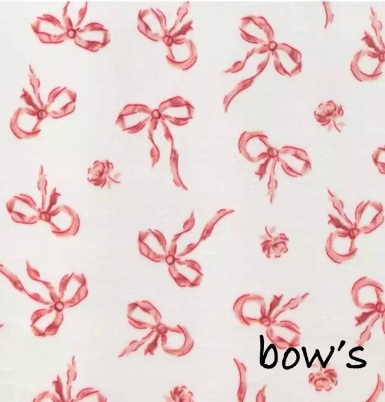 May include: White fabric with a repeating pattern of watercolor-style red bows and small roses. The word "bow's" is written in black script at the bottom right corner of the image. The bows vary in size and style.