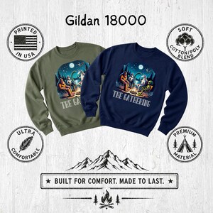 K&ouml;nnte beinhalten: Zwei Gildan 18000 Rundhals-Sweatshirts in Olivgr&uuml;n und Marineblau. Beide zeigen eine Grafik von Bigfoot, einem Alien und einem Einhorn, die unter einem Sternenhimmel um ein Lagerfeuer sitzen, mit dem Schriftzug THE GATHERING unter dem Motiv.