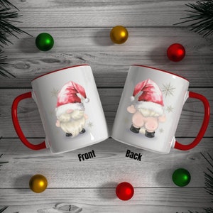May include: White ceramic mug with a red rim and handle. The mug features a cartoon illustration of a gnome wearing a red Santa hat and a white beard. The front of the mug shows the gnome's face, while the back shows the gnome's backside. The words "Front" and "Back" are printed below the mug.