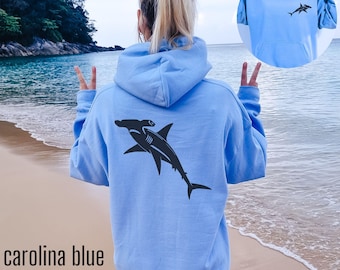 May include: Carolina blue hoodie with a black hammerhead shark graphic on the back. The hoodie has a small shark design on the front. The text "carolina blue" is at the bottom of the image.