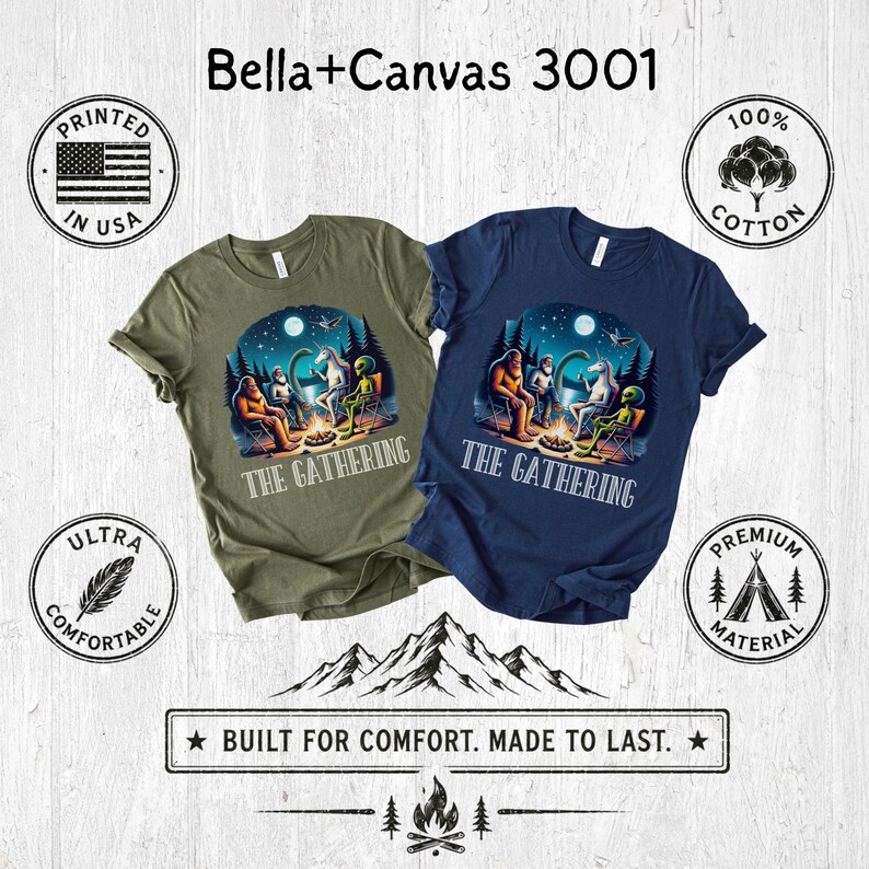 K&ouml;nnte beinhalten: Zwei kurz&auml;rmelige T-Shirts, eines in Olivgr&uuml;n und eines in Marineblau, mit einer Grafik von Bigfoot, einem Einhorn und einem Alien, die unter einem Nachthimmel um ein Lagerfeuer sitzen. Der Text THE GATHERING steht unter der Grafik.