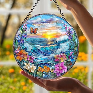May include: Round stained glass window art depicting a sunset over the ocean, with a butterfly and colorful flowers. The artwork is held by a chain and features shades of blue, orange, and purple.