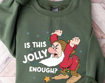 May include: Green sweatshirt featuring a graphic of Grumpy from Snow White, holding Christmas lights. The text "IS THIS JOLLY ENOUGH?" is printed in white. The sweatshirt has long sleeves and a crew neck.