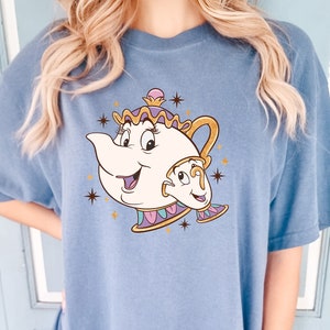 May include: A blue t-shirt with a cartoon image of Mrs. Potts and Chip from Beauty and the Beast. The image is surrounded by gold stars.