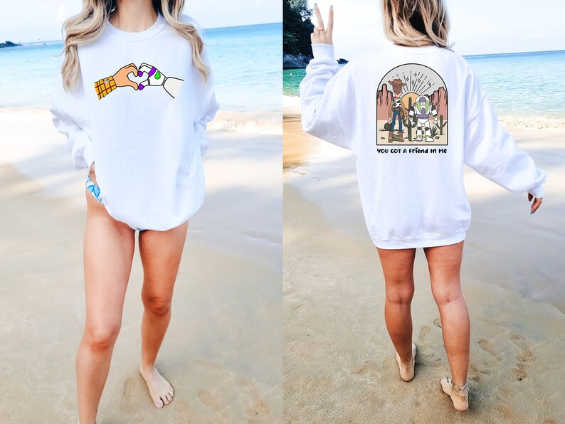 May include: White sweatshirt with a graphic of Woody and Buzz Lightyear from Toy Story on the front. The back of the sweatshirt has a graphic of Woody and Buzz Lightyear with the text "You got a friend in me".