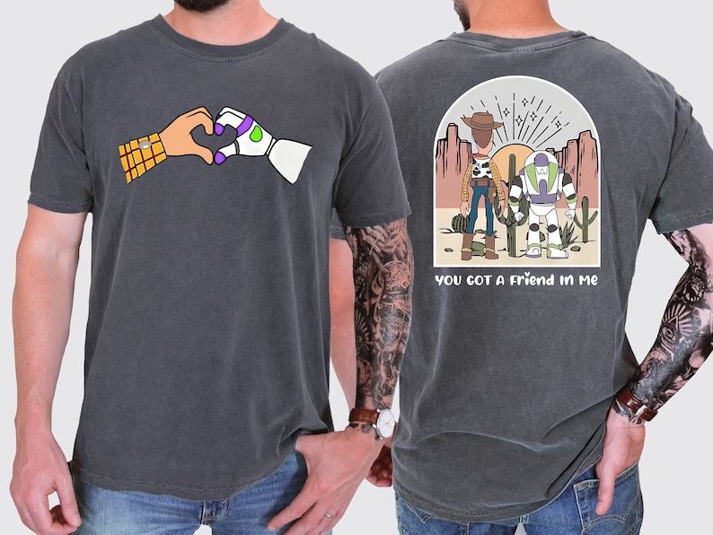 May include: A dark grey t-shirt with a cartoon image of Woody and Buzz Lightyear from Toy Story on the back. The back of the shirt also has the text "You got a friend in me". The front of the shirt has a cartoon image of Woody and Buzz Lightyear making a heart shape with their hands.