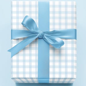 May include: A wrapped gift box with a light blue and white gingham pattern. The box is tied with a light blue satin ribbon and bow. The words "Brew Paper" are written in cursive on the bottom right corner.