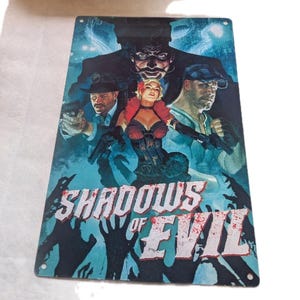 May include: A metal sign featuring a vintage-style illustration with the text "Shadows of Evil." The artwork depicts several figures with guns, set against a blue and teal background. The sign has four corner holes for hanging.