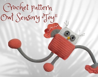 May include: Crocheted owl sensory toy with gray and pink yarn. The owl has large eyes, a beak, and two long arms. The toy is hanging in the air.