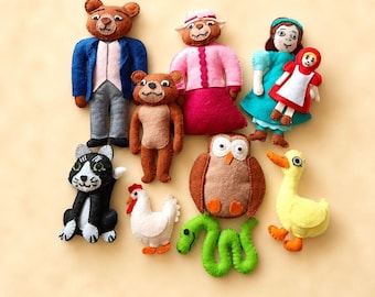 May include: A collection of felt plush figures including a bear in a blue jacket, a bear in a pink outfit, a person in a teal dress holding a small doll, a black and white cat, a white chicken, a brown owl, a green snake, and a yellow duck.