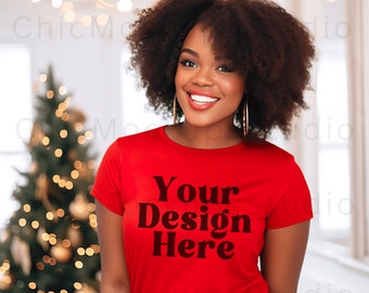 May include: A woman with curly hair is wearing a red t-shirt with the text "Your Design Here" printed on the front. She is standing in front of a Christmas tree with lights.
