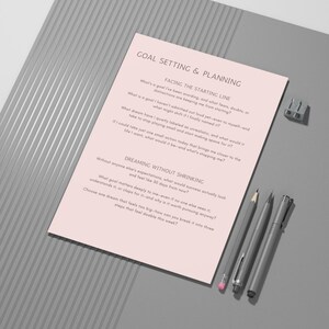 Op de afbeelding: Een roze werkblad voor doelstelling en planning met tekst, een potlood, twee pennen en een puntenslijper op een grijze ondergrond. Het werkblad bevat vragen voor zelfreflectie en doelstelling.