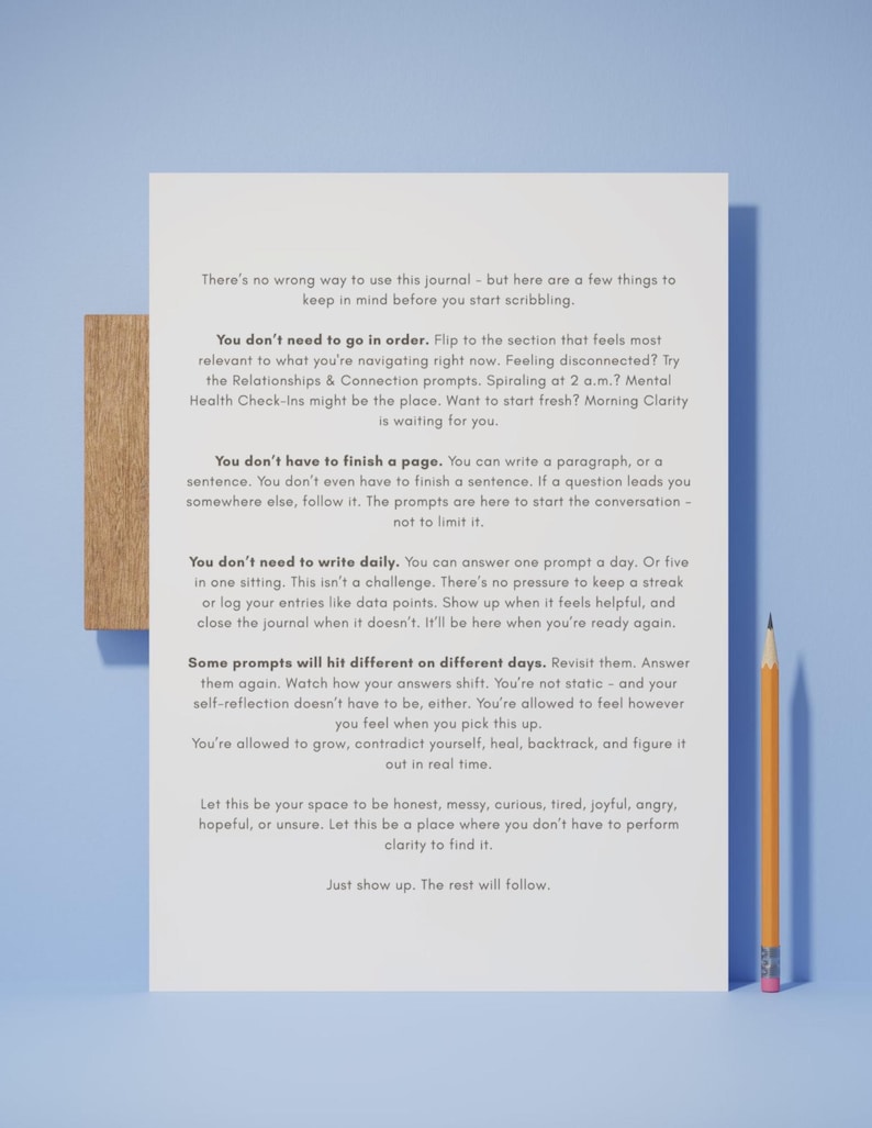 Op de afbeelding: Een dagboek met tekst en een houten basis, vergezeld van een gele en oranje potlood. De pagina's van het dagboek staan vol tekst met richtlijnen voor zelfreflectie en journaling. De achtergrond is lichtblauw.