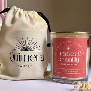 May include: A candle in a clear glass jar with a gold rim, labelled "Fraises & chantilly" with a red label. Beside it is a beige drawstring bag with the "Quimera Candles" logo.