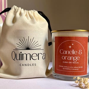 K&ouml;nnte beinhalten: Eine Kerze im Glas mit goldenem Rand, beschriftet mit "Canelle & orange", neben einem Kordelzugbeutel mit dem Logo "Quimera Candles". Das Kerzenetikett listet Zutaten und ein Gewicht von 210 g auf.