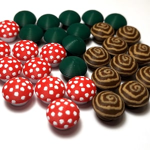 Puede incluir: Una colección de objetos decorativos con forma de hongo en rojo con lunares blancos, verde y marrón con patrones de remolino. Los objetos están dispuestos sobre una superficie blanca, mostrando sus diversos diseños y colores. Probablemente sean artículos decorativos.