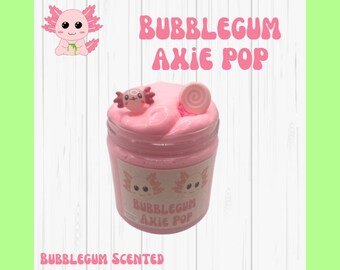 May include: Pink slime with a swirl of white on top in a clear jar with a pink label that says "Bubblegum Axolotl Pop" and a cartoon axolotl on the label. The jar is on a white wooden surface. Bubblegum Scented.