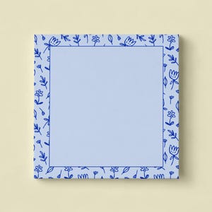 Peut inclure: Un bloc-notes carré bleu clair avec une bordure florale bleu foncé. La bordure présente un motif répétitif de fleurs et de feuilles. Le centre du bloc-notes est de couleur bleu clair uni.