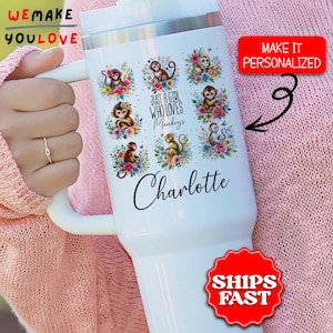 May include: White tumbler with a handle featuring monkey illustrations surrounded by flowers. Text reads "JUST A GIRL WHO LOVES Monkeys" and "Charlotte". A red sticker says "MAKE IT PERSONALIZED".