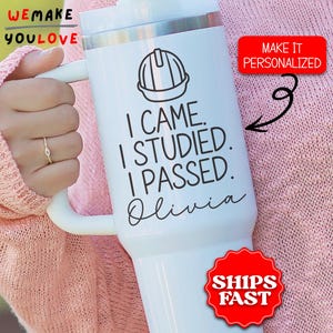 May include: White insulated tumbler with a handle, featuring a hard hat graphic and the text "I CAME. I STUDIED. I PASSED. Olivia." A red sticker says "MAKE IT PERSONALIZED." Another red sticker says "SHIPS FAST."