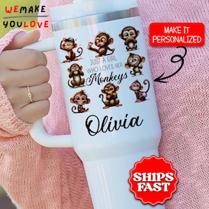 May include: White tumbler featuring cartoon monkeys and the text "Just a girl who loves her Monkeys" and the name "Olivia". The tumbler has a white handle and lid. The image also includes the text "We Make You Love" and "Make it Personalized".
