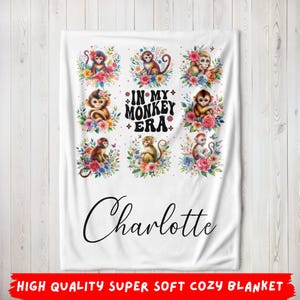 May include: White fleece blanket with a floral design and monkeys. The text "In My Monkey Era" is in black lettering. The name "Charlotte" is written in black cursive lettering at the bottom of the blanket.