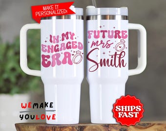 May include: Two white travel mugs with handles, featuring pink text and ring graphics. One mug reads "IN MY ENGAGED ERA" and the other says "FUTURE mrs Smith". A red banner says "MAKE IT PERSONALIZED!"