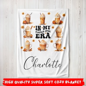 Könnte beinhalten: Weiße Fleece-Decke mit einem herbstlichen Design mit mehreren Illustrationen von Pumpkin Spice Lattes und dem Text "In My Pumpkin Spice Era" mit dem Namen "Charlotte" unten.