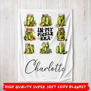 May include: White fleece blanket with a green pickle design and the text "In My Pickle Era" and the name "Charlotte".