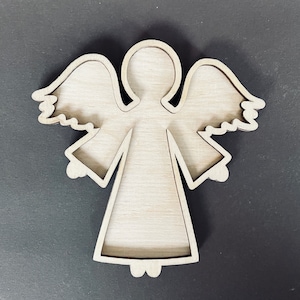 May include: Wooden cutout of an angel with wings, a halo, and a dress. The cutout is unfinished and ready to be painted or decorated.