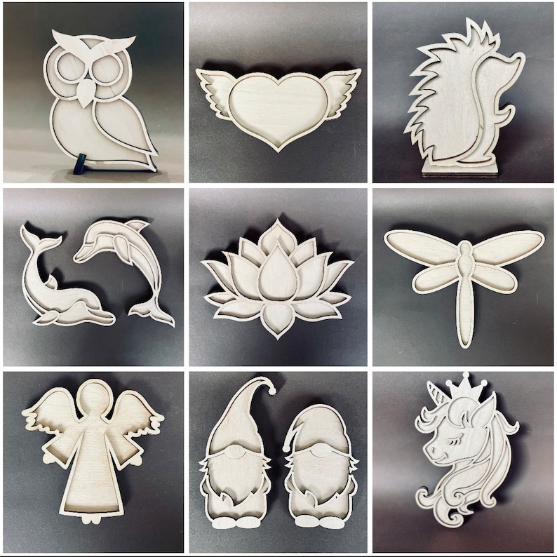 May include: Nine wooden cutout shapes, including an owl, a heart with wings, a hedgehog, a dolphin, a lotus flower, a dragonfly, an angel, two gnomes, and a unicorn. The shapes are all cut from a light brown wood and have a smooth, unfinished surface.