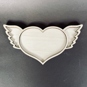 May include: A wooden heart-shaped tray with wings. The tray is made of light wood and has a natural finish.