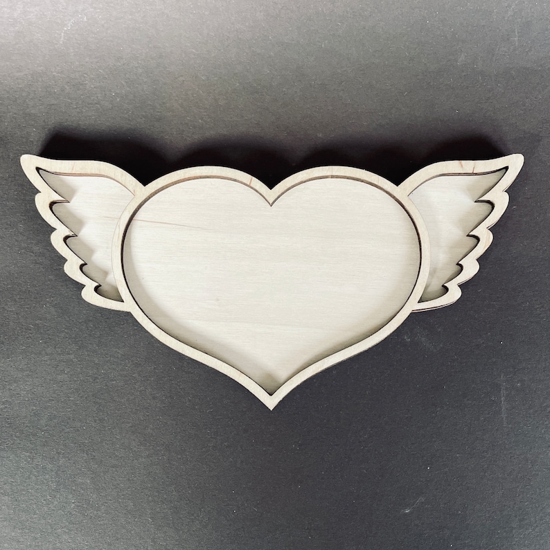 May include: A wooden heart-shaped tray with wings. The tray is made of light wood and has a natural finish.