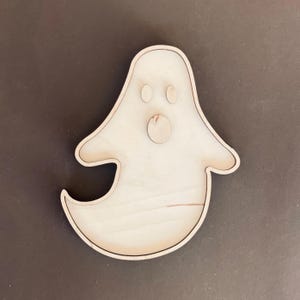May include: A wooden ghost shaped tray with a round cutout for the mouth and two smaller cutouts for eyes.