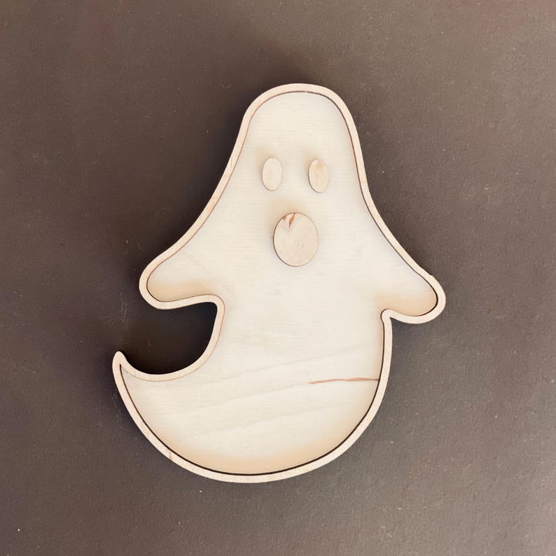 May include: A wooden ghost shaped tray with a round cutout for the mouth and two smaller cutouts for eyes.