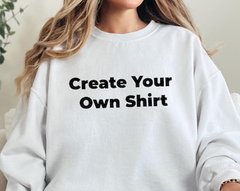May include: A white sweatshirt with the text "Create Your Own Shirt" in black. The sweatshirt is a crew neck style and is being worn by a person. The person is wearing blue jeans with ripped knees.