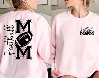 May include: Light pink sweatshirt with the text "Football Mom" in black. The design includes a football and a heart. The back of the sweatshirt has a larger design with the word "Football" and the letters "MOM" with a football and heart.