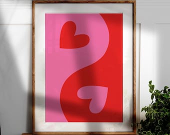 Könnte beinhalten: Ein gerahmter Kunstdruck mit einem Yin-Yang-Design mit zwei Herzformen. Das Kunstwerk ist in zwei Abschnitte unterteilt, einen rosa und einen roten, mit einer Herzform in jedem Abschnitt. Der Rahmen ist hellbraun.