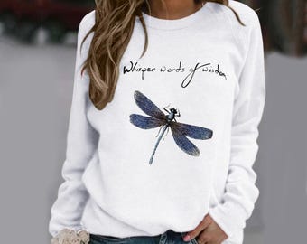 May include: White long-sleeve sweatshirt with a blue dragonfly graphic and the text "Whisper words of wisdom".