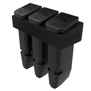 Puede incluir: Un soporte de cargador negro con tres ranuras, cada una con un cargador negro. La parte superior del soporte tiene tres secciones rectangulares con la palabra "GLOCK" impresa. El lateral del soporte tiene el texto "MAG TEK".