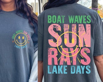 May include: A dark gray oversized t-shirt with a graphic print of a smiley face and the text "Boat Waves Sun Rays Lake Days". The graphic is in pink, yellow, green, and blue.