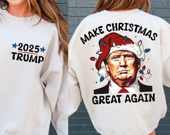 May include: White sweatshirt with the text "MAKE CHRISTMAS GREAT AGAIN" on the back and a cartoon image of Donald Trump wearing a Santa hat. The front of the sweatshirt has the text "*2025* TRUMP" in black and blue.