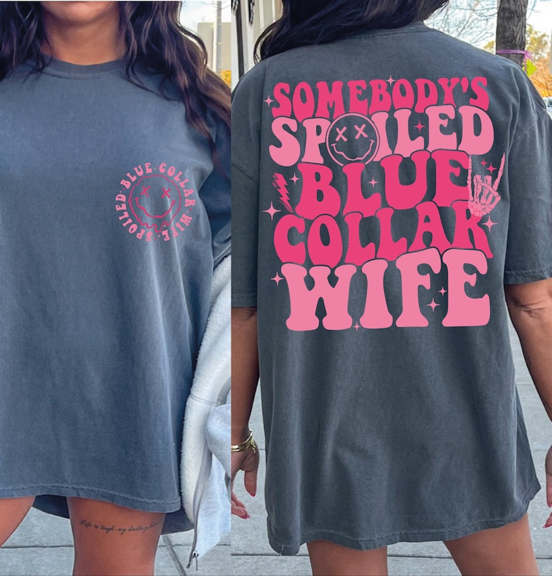 May include: An oversized grey t-shirt with a pink graphic that says "Somebody's Spoiled Blue Collar Wife" with a smiley face and a lightning bolt.