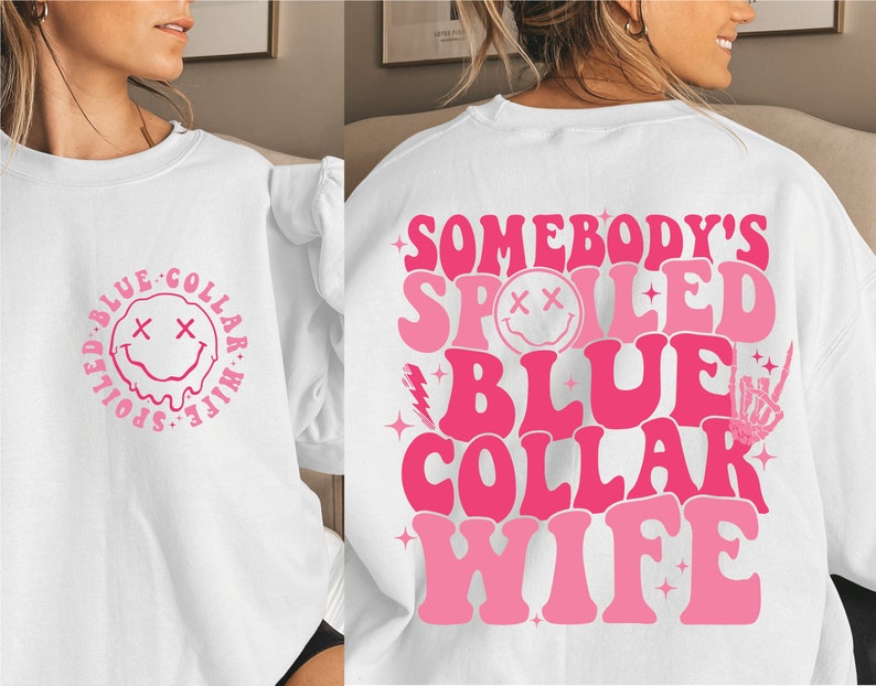 May include: White sweatshirt with pink text that reads "Somebody's Spoiled Blue Collar Wife" with a pink smiley face and other pink graphic elements.